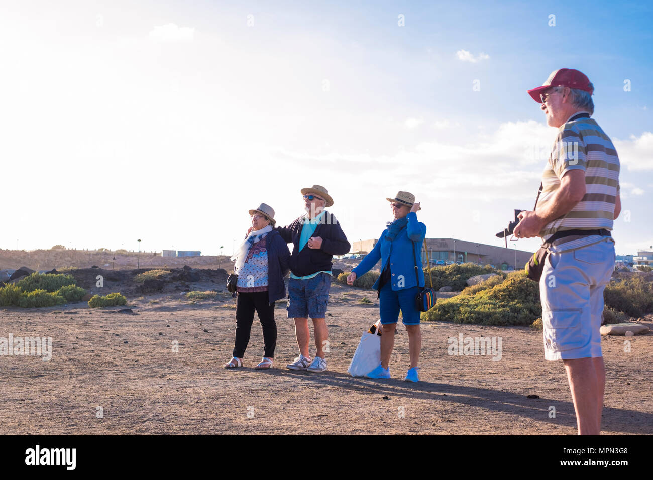 4 Senioren verbringen freie Zeit am Strand beobachten und Pilotierung der Drohne Stockfoto