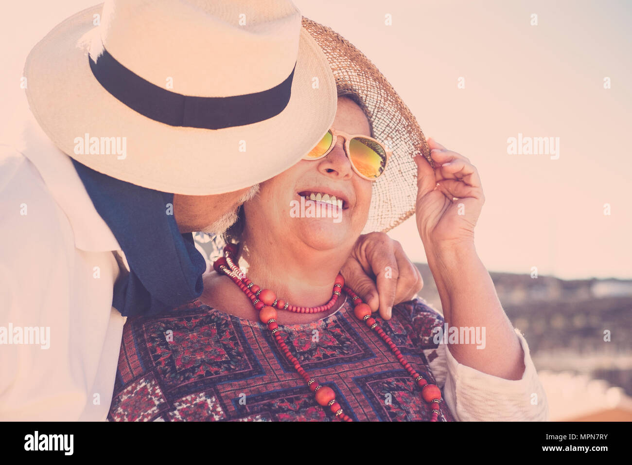 Erwachsene Menschen zusammen mit Kuss und Umarmung unter der Sonne Aufenthalt mit Hut und Sonnenbrille und Halskette. Wahre Liebe für immer zusammen Konzept Stockfoto