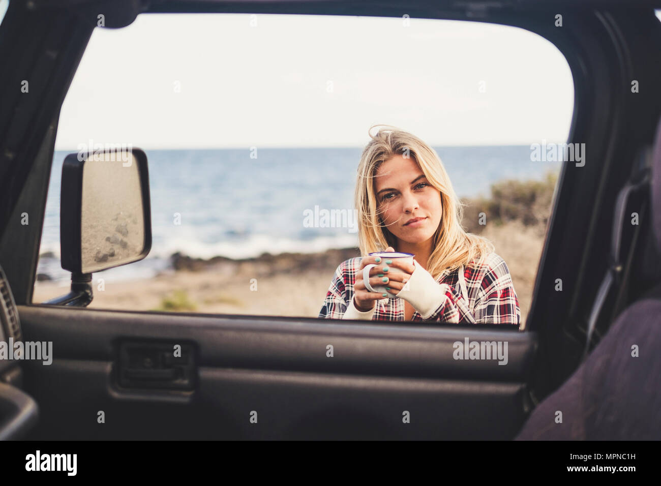 Freiheit und Ferienhäuser Konzept für schöne Blondine kaukasischen junge Frau outsidef einer off road Black Car. Hintergrundbeleuchtung und Sonnenlicht in warmen Tönen Stockfoto