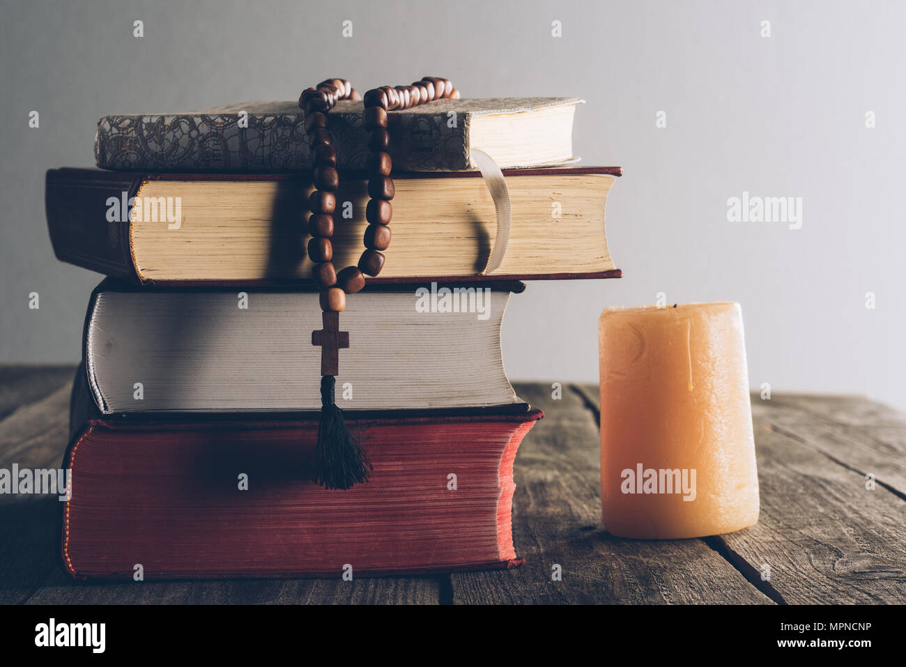 Stapel der religiösen Bücher und christliche Kreuz auf hölzernen Tisch Stockfoto