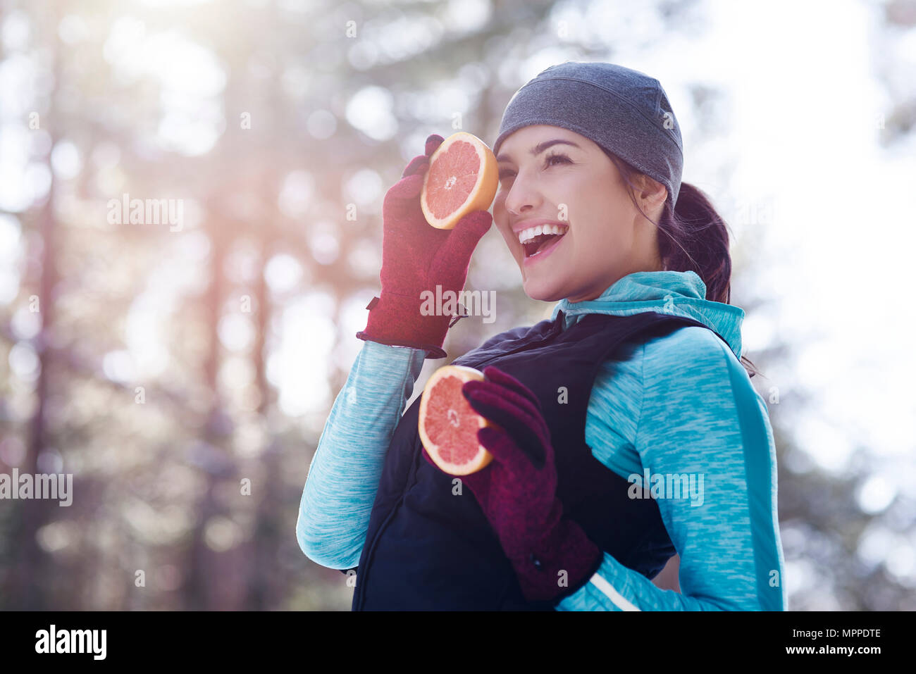 Portrait von Lachende junge Frau trägt Sportkleidung, die zwei Hälften Grapefruit Stockfoto