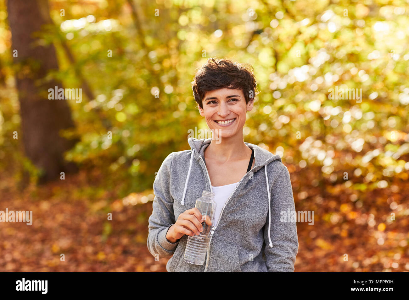 Lächelnd weibliche Jogger mit Wasserflasche Stockfoto