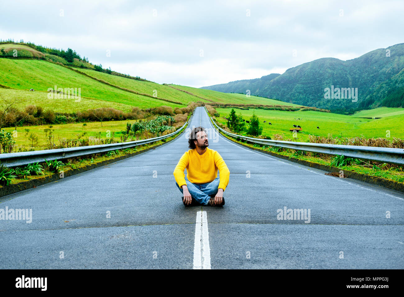 Azoren, Sao Miguel, Mann sitzt auf einer leeren Straße Stockfoto