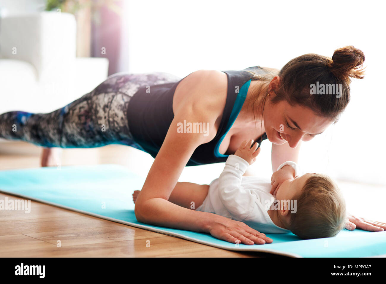 Mutter mit Baby der Ausübung von Yoga Matte zu Hause Stockfoto