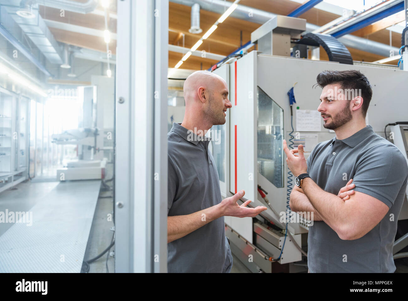 Zwei Männer diskutieren an der Maschine in der modernen Fabrik Stockfoto