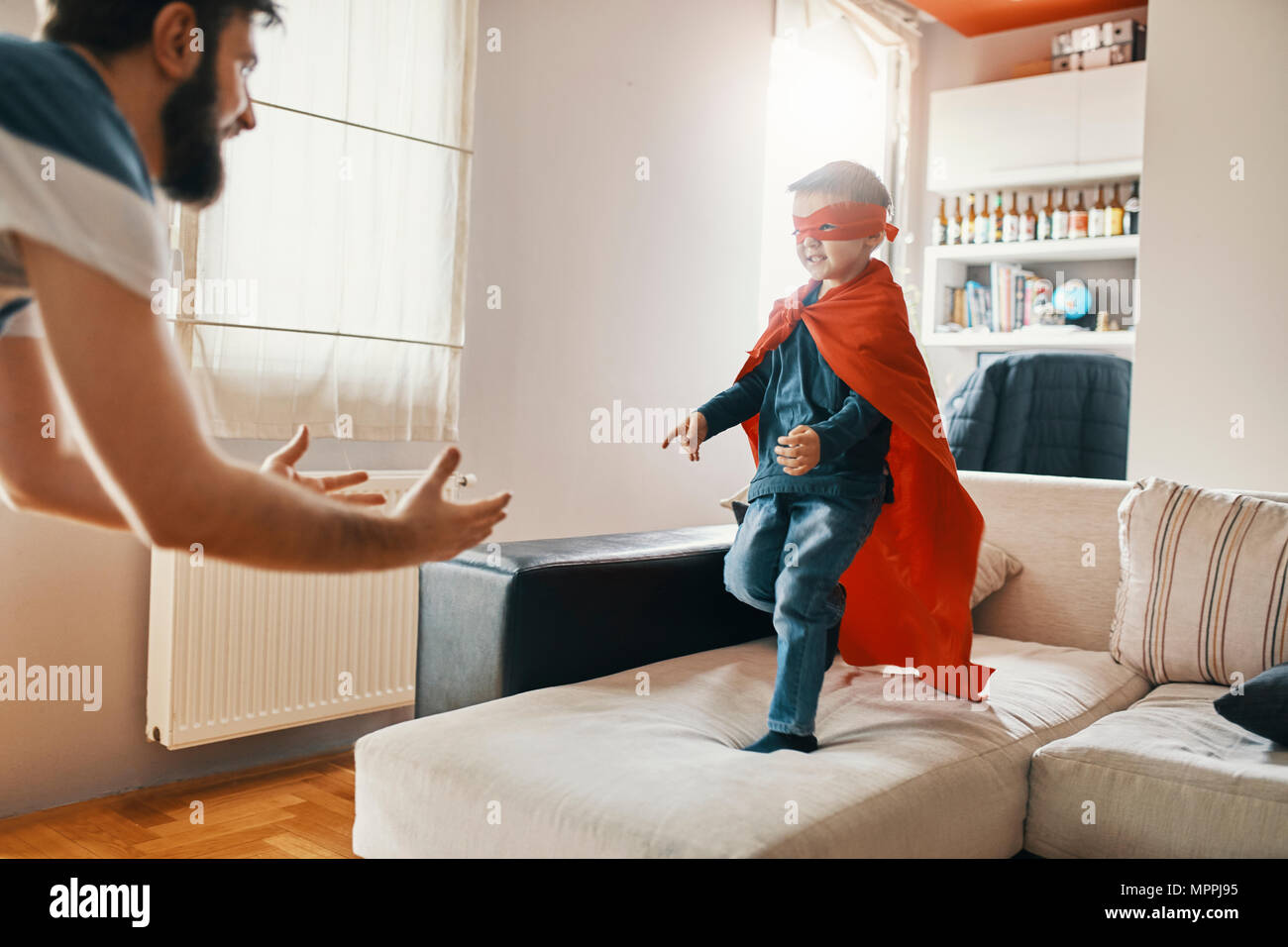 Vater mit seinem kleinen Sohn als Superheld zu Hause angezogen Stockfoto