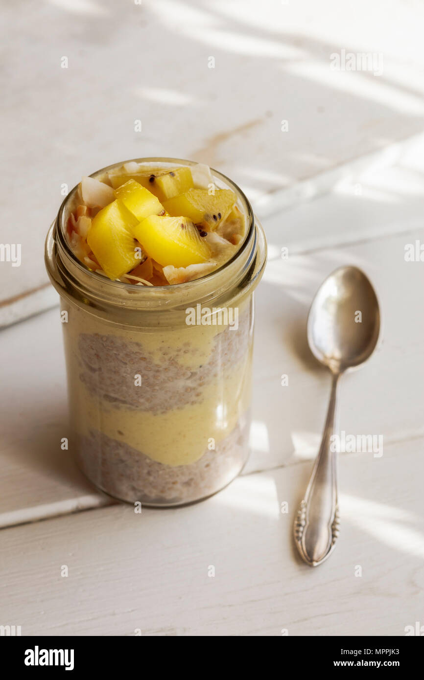Glas von Chia Pudding mit Mango Smoothie garniert mit Kiwi und Kokosraspeln Stockfoto