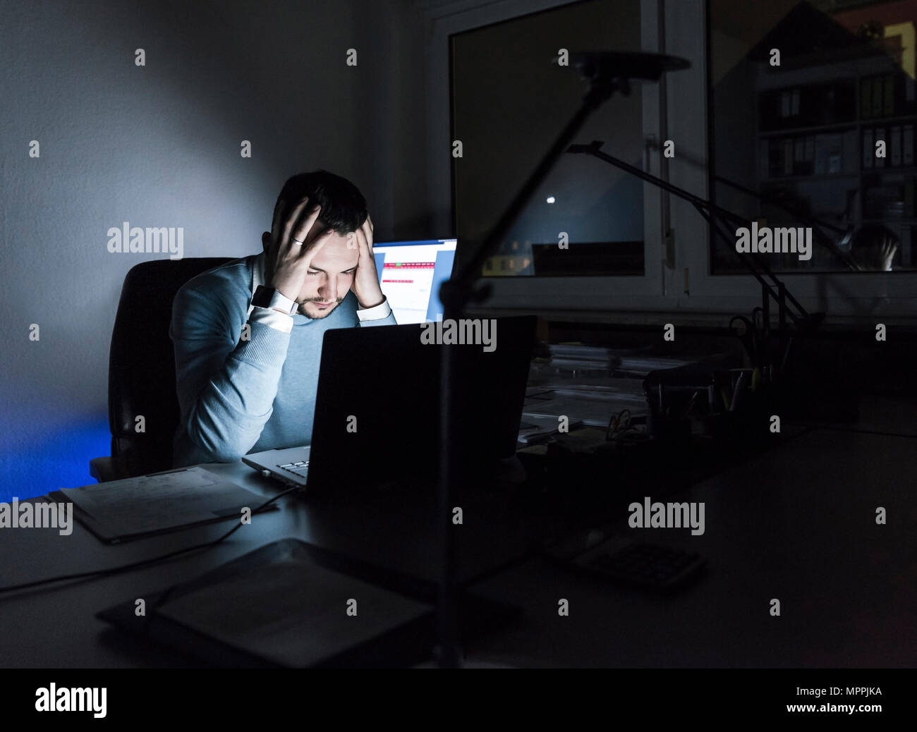 Müde Geschäftsmann am Schreibtisch im Büro in der Nacht Stockfoto