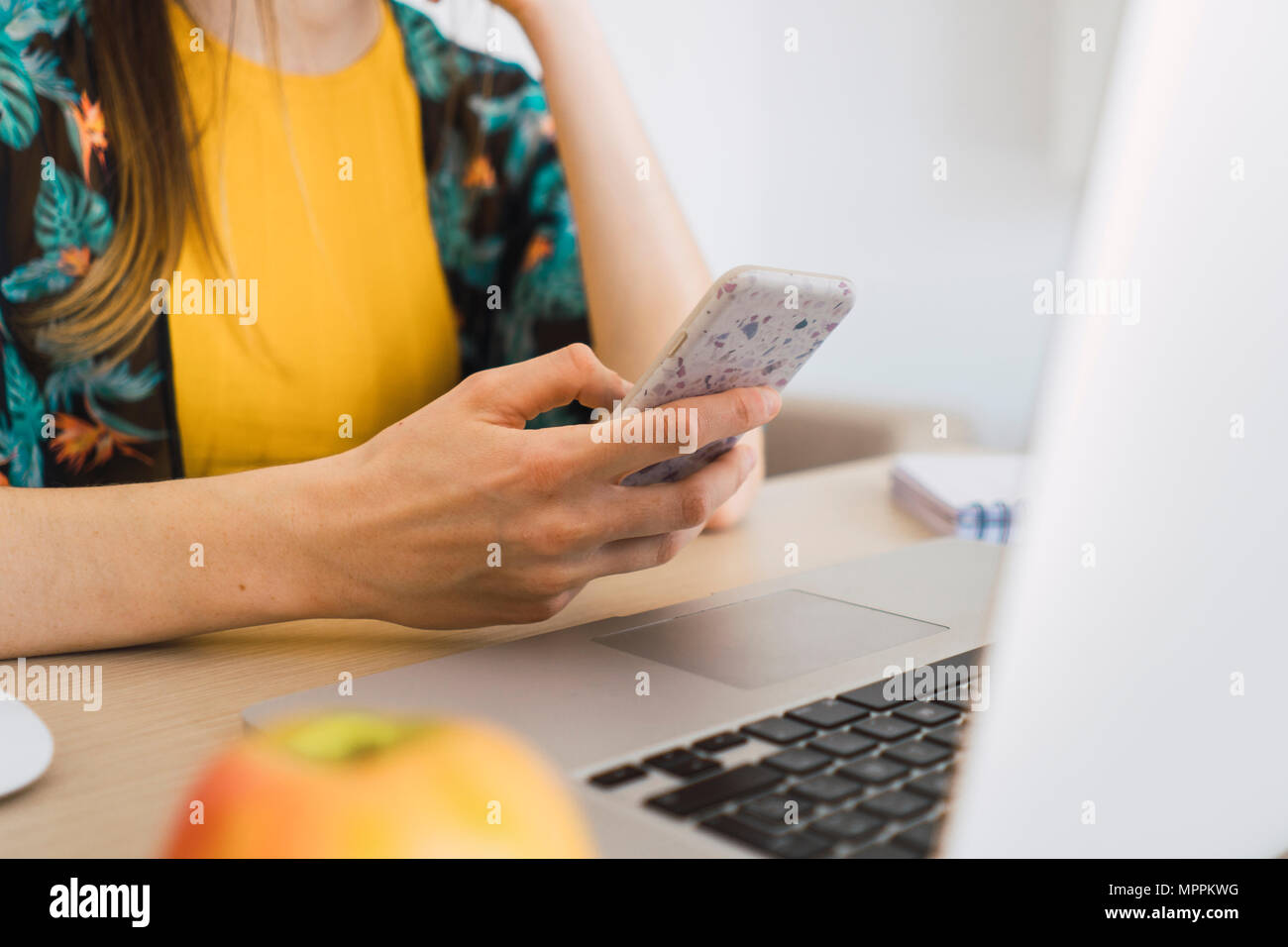 In der Nähe von Frau sitzt am Tisch zu Hause mit Handy und Laptop Stockfoto