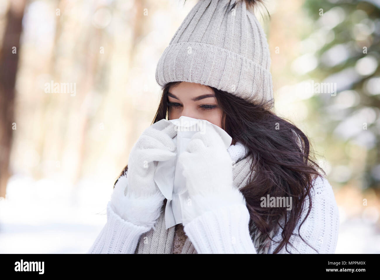 Junge Frau blasen Nase im Winter Stockfoto