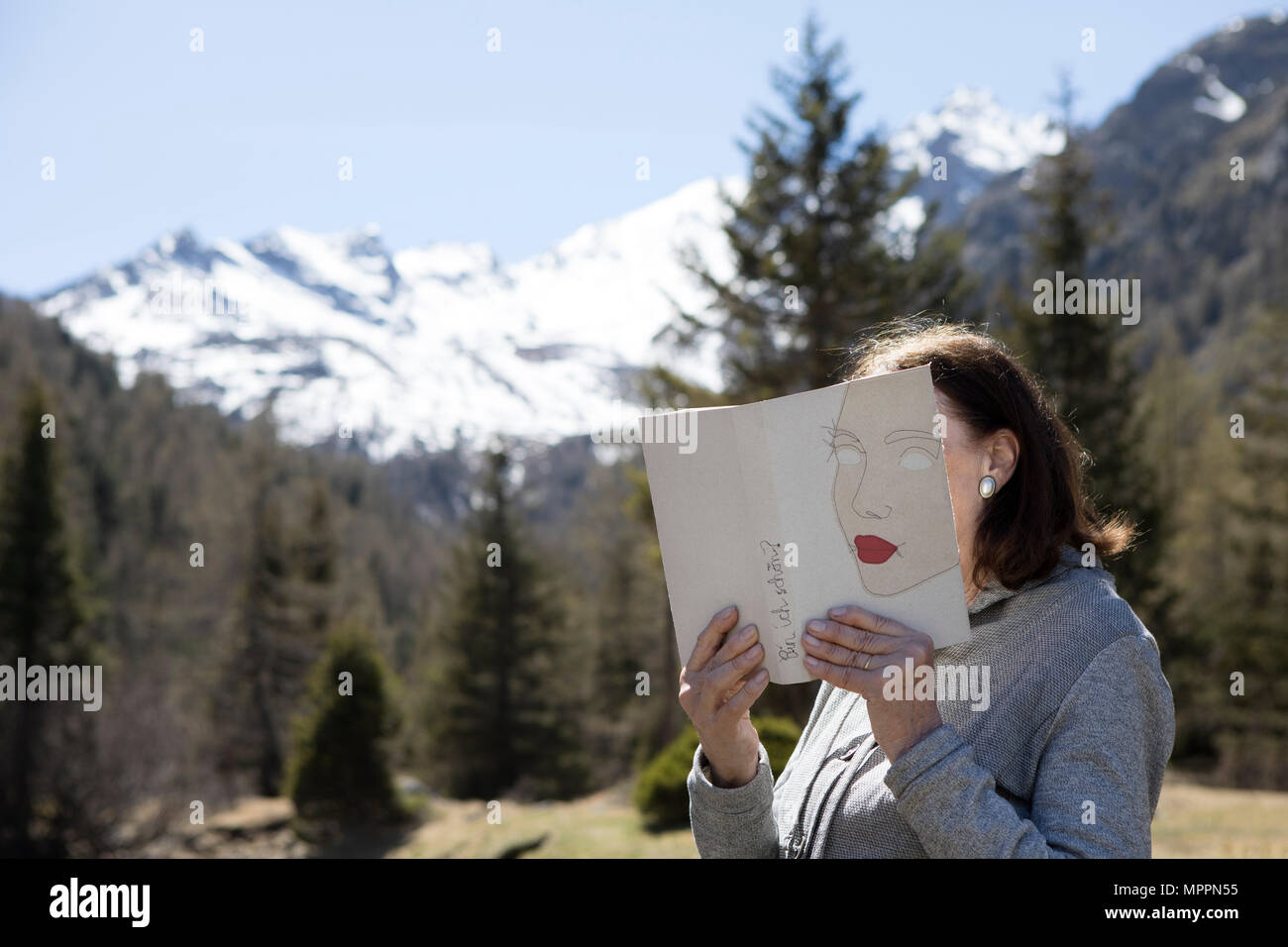 Frau mit Gesicht mit Buch, lesen Poesie in den Bergen Stockfoto
