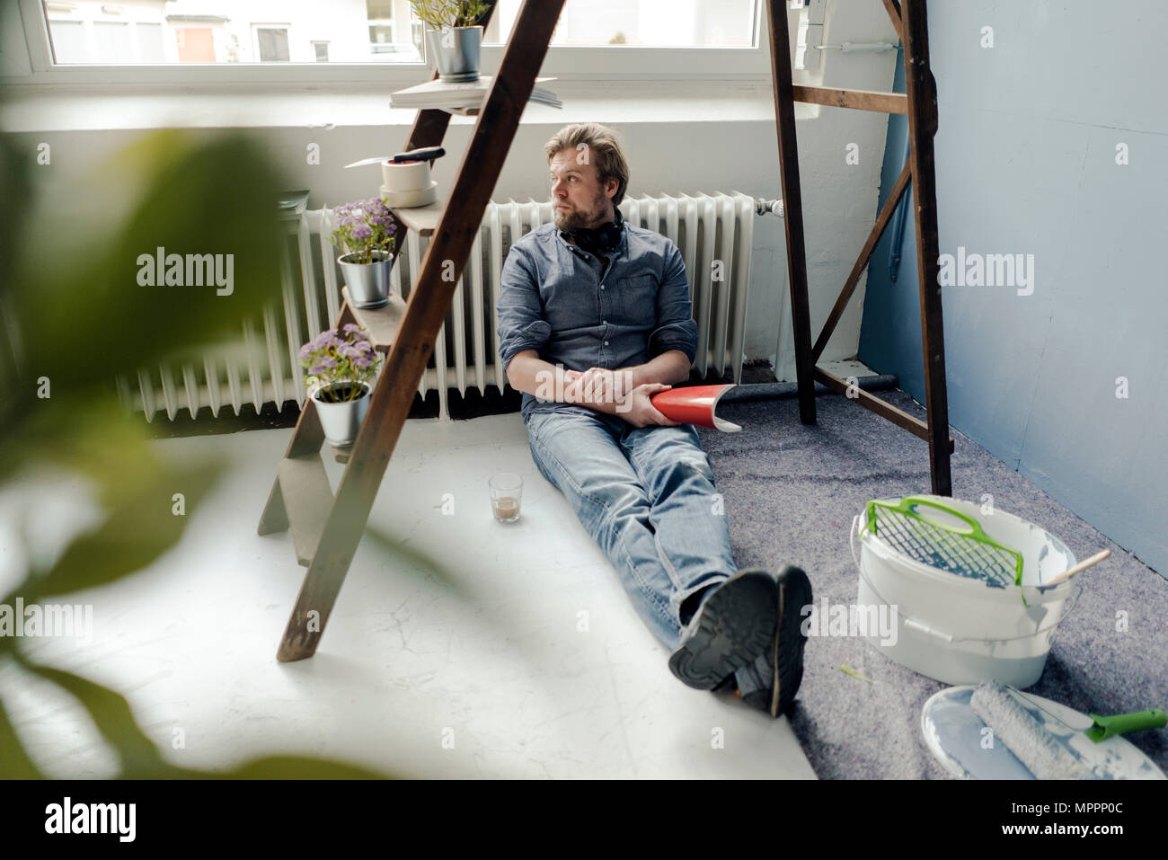 Mann renovieren Zimmer auf dem Boden sitzend mit einem Rest Stockfoto