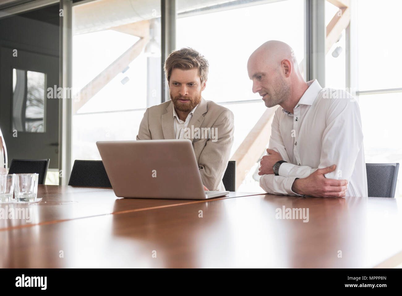 Zwei Geschäftsleute teilen Laptop im Konferenzraum Stockfoto