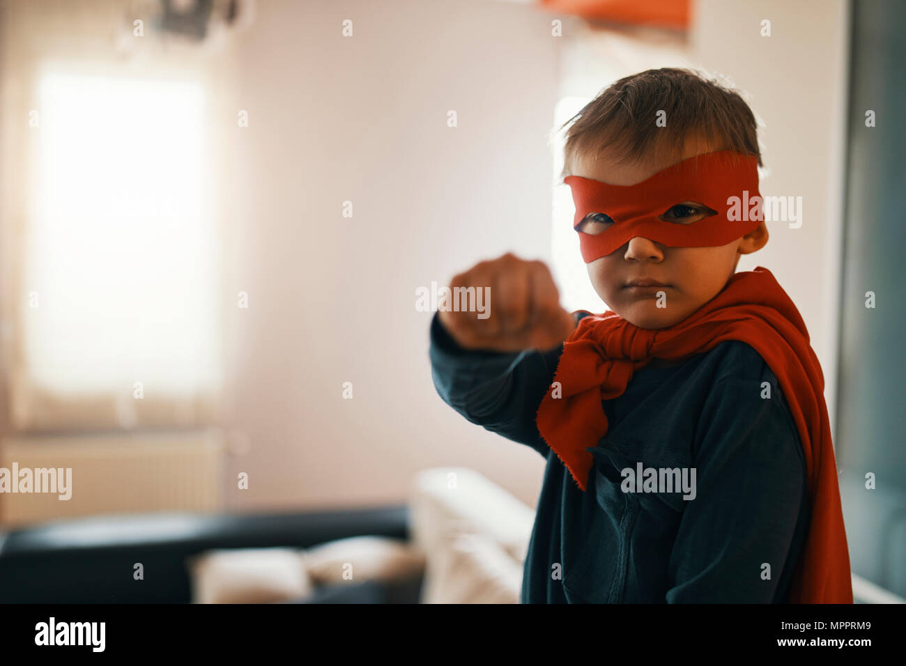 Portrait von kleinen Jungen, die so tut, als wäre sie ein Superheld zu Hause Stockfoto