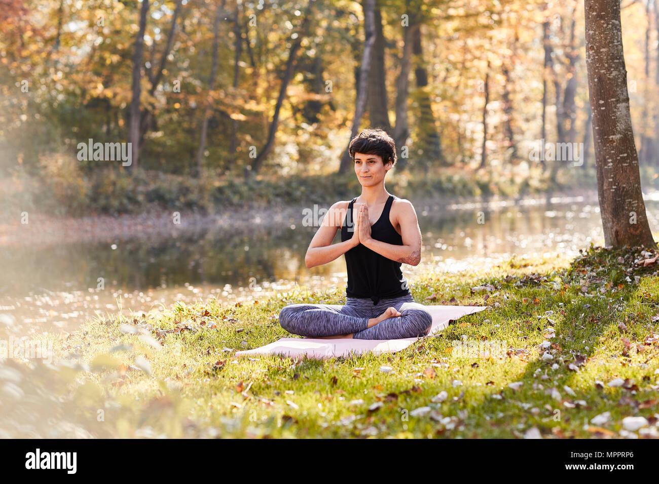 Mitte der erwachsenen Frau im Wald Üben Yoga, Meditation Stockfoto