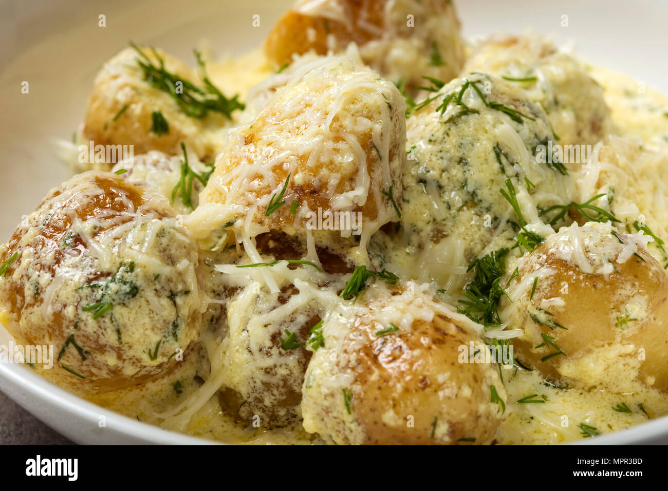 Baby neue Kartoffeln mit saurer Sahne und Käse Sauce in der Platte - Nahaufnahme Stockfoto