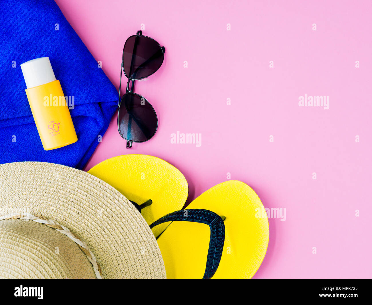 Sonnenbrille mit Sommer Hut, Sonnencreme, blau Handtuch und Badelatschen auf rosa Hintergrund. Urlaub und Entspannung, Sommer Travel Concept. Stockfoto
