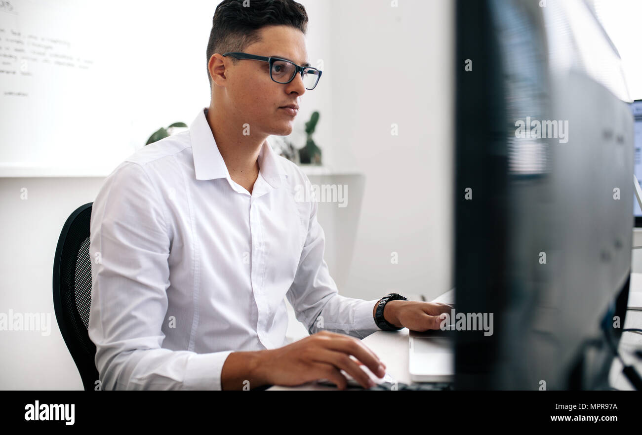 Software Entwickler sitzen vor dem Computer und Arbeiten im Büro. Mann mit Brille arbeiten am Laptop und Computer im Büro. Stockfoto