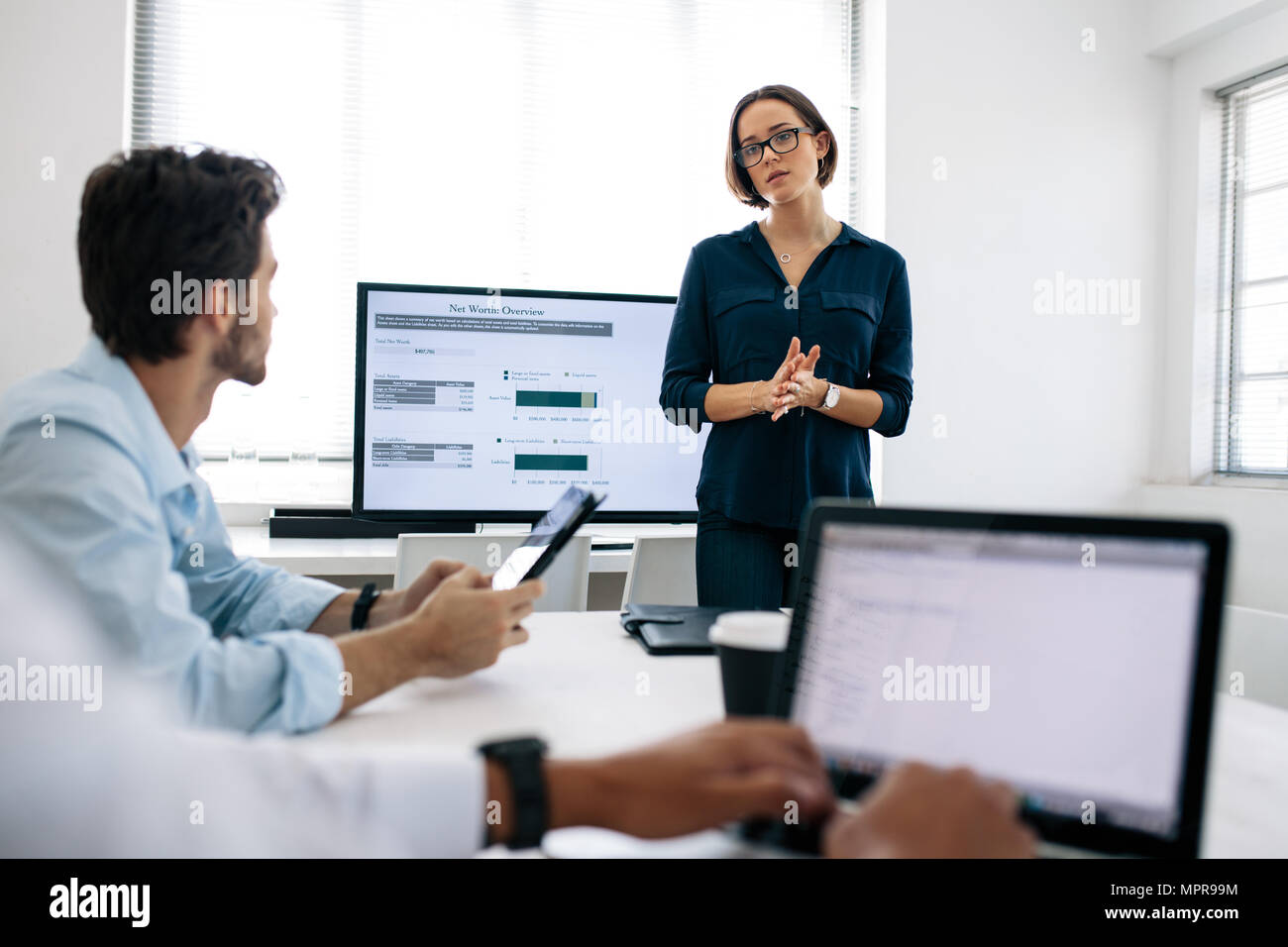 Geschäftsfrau Tragen einer Brille eine Präsentation, die ihre Kollegen im Büro. Büro Kollegen bei Laptops während der Wiedergabe Stockfoto
