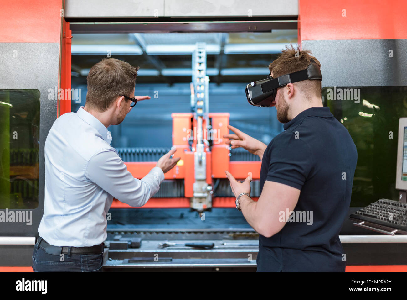 Mann erklären, Maschine an Kollegen tragen VR-Brille in der Factory Stockfoto