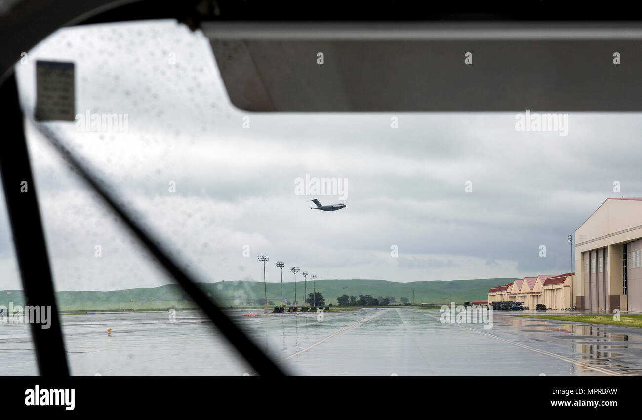 Eine c-17 Globemaster gesehen durch eine Besatzung Bus Windschutzscheibe lässt an einem regnerischen Morgen, 7. April 2017 Travis Air Force Base. Die Boeing c-17 Globemaster III ist eine große militärische Transportflugzeuge. Es wurde von McDonnell Douglas für die United States Air Force (USAF) aus den 1980er Jahren zu den frühen 1990er Jahren entwickelt. Die c-17 trägt den Namen der zwei vorherigen Kolbenmotor militärische Frachtflugzeuge, die Douglas C-74 Globemaster und Douglas C-124 Globemaster II. Die c-17 führt häufig strategische Luftbrücke Missionen, den Transport von Truppen und Fracht in der ganzen Welt; zusätzliche Rollen gehören taktische Ki Stockfoto