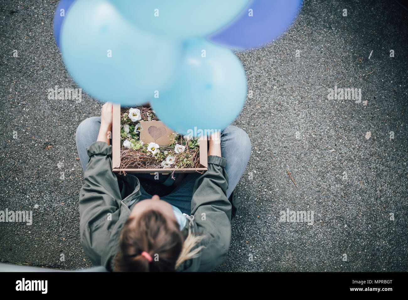 Frau mit in den Karton und blaue Luftballons auf dem Boden sitzend Stockfoto