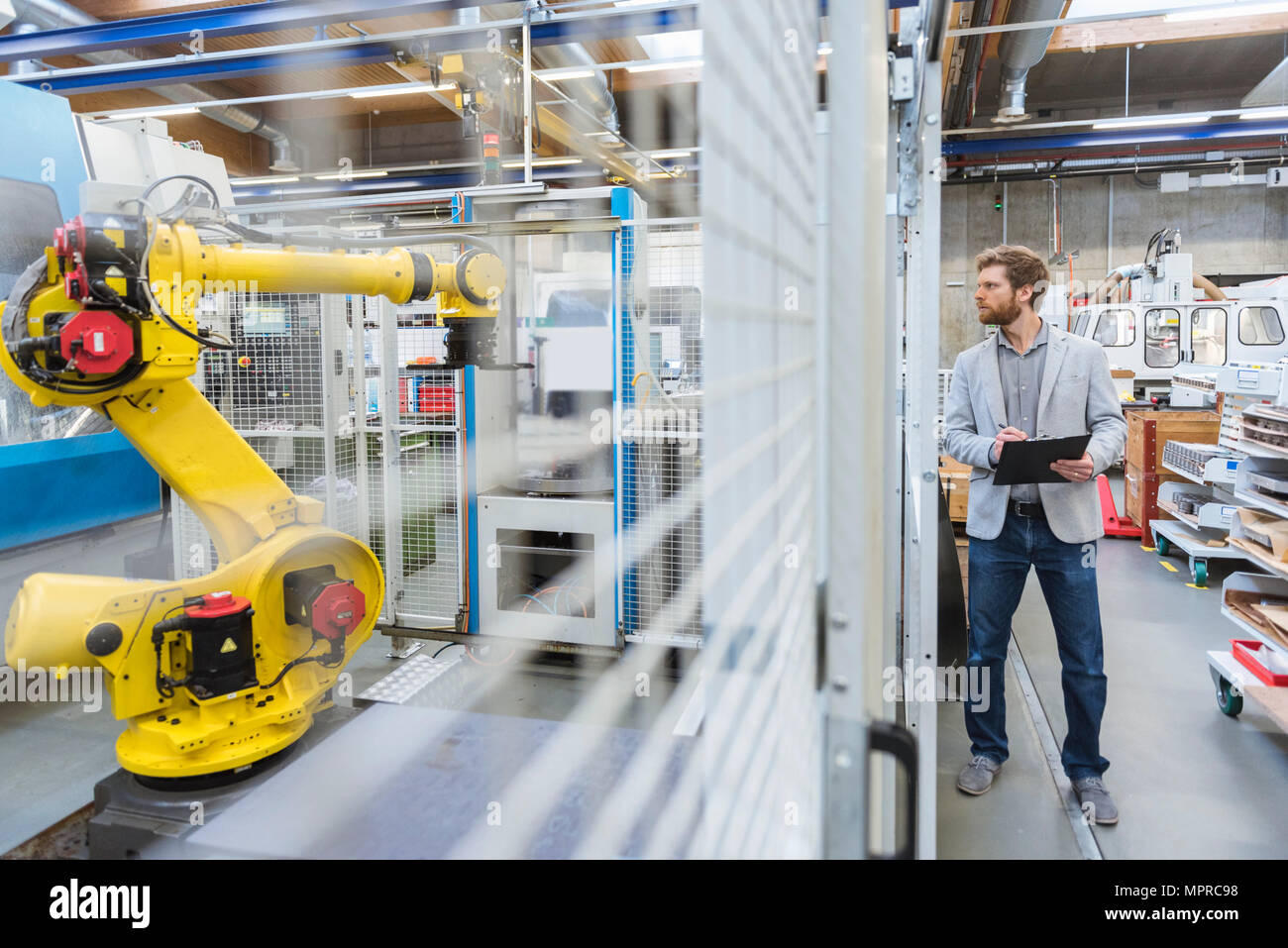Geschäftsmann an Industrieroboter in der modernen Fabrik suchen Stockfoto