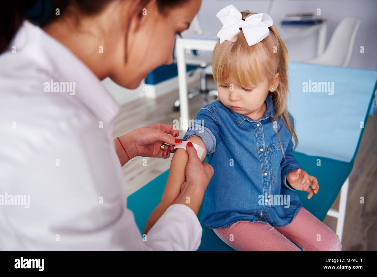 Arzt Anwendung band-aid auf Girl's Arm in die medizinische Praxis Stockfoto