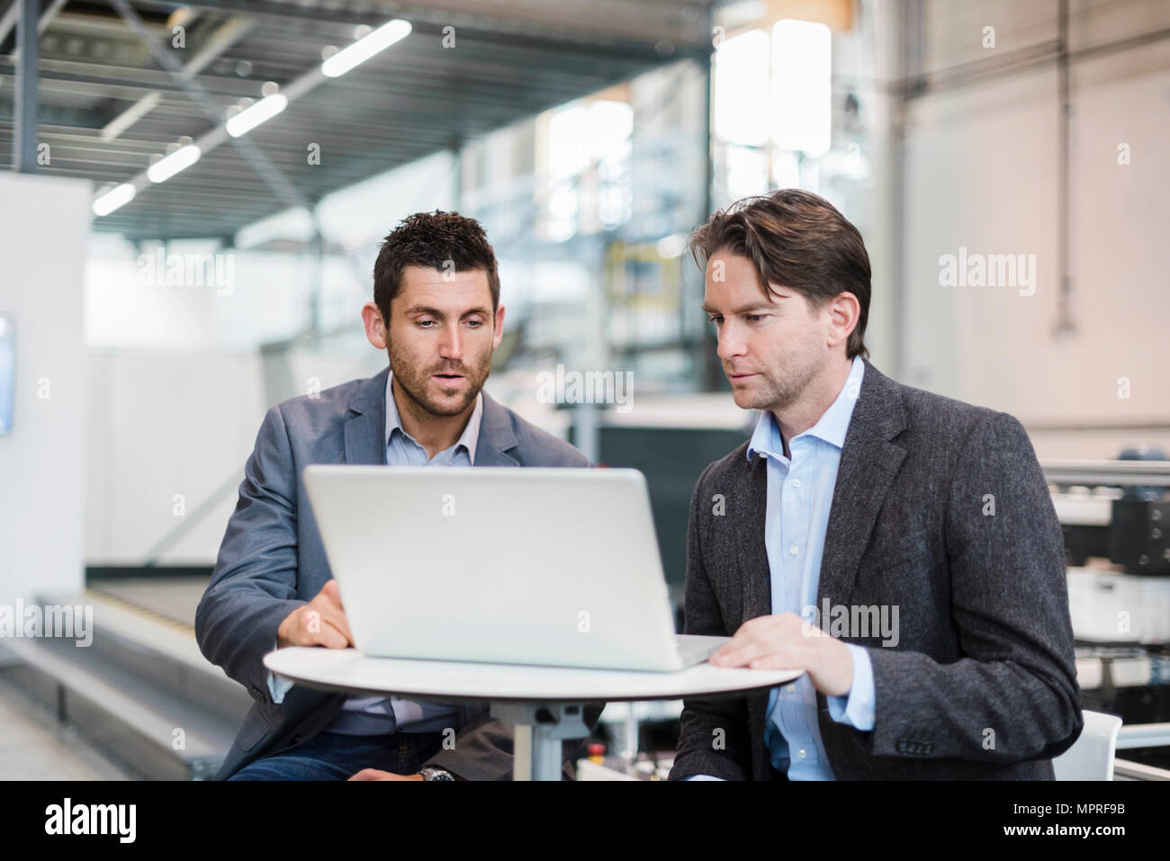Zwei Geschäftsleute teilen Laptop in der Factory Stockfoto