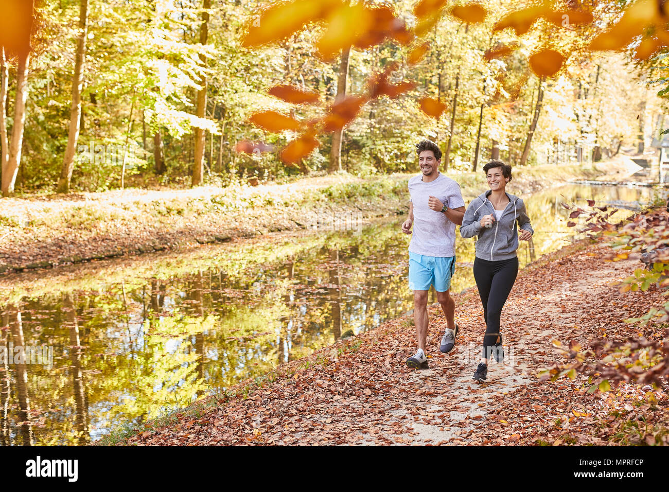 Paar Jogging auf autumnally Waldweg Stockfoto