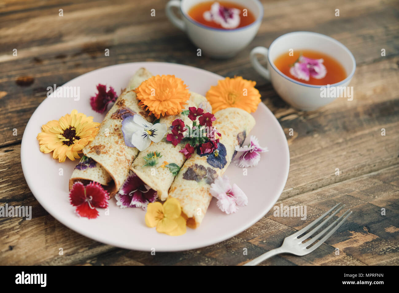 Pfannkuchen mit essbaren Blüten und Infusion von roten Blumen Stockfoto