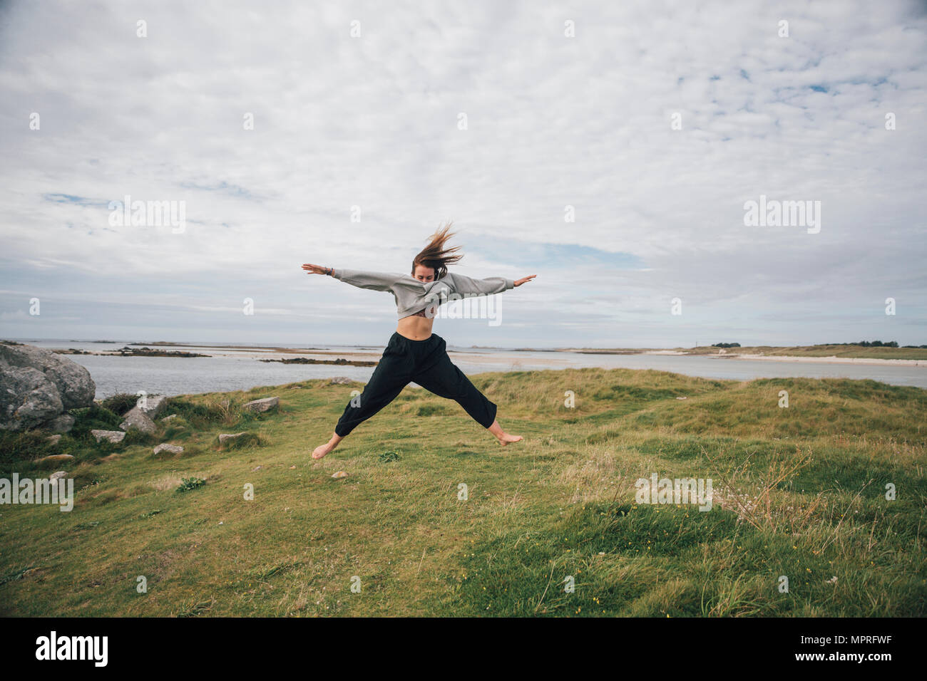 Frankreich, Bretagne, Landeda, Dünen de Sainte-Marguerite, junge Frau an der Küste springen Stockfoto