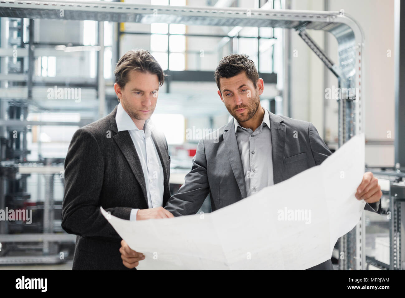 Zwei Geschäftsleute suchen Bei Plan in der modernen Fabrik Stockfoto