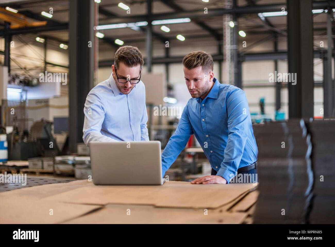 Zwei Geschäftsleute teilen Laptop auf Factory Shop Boden Stockfoto