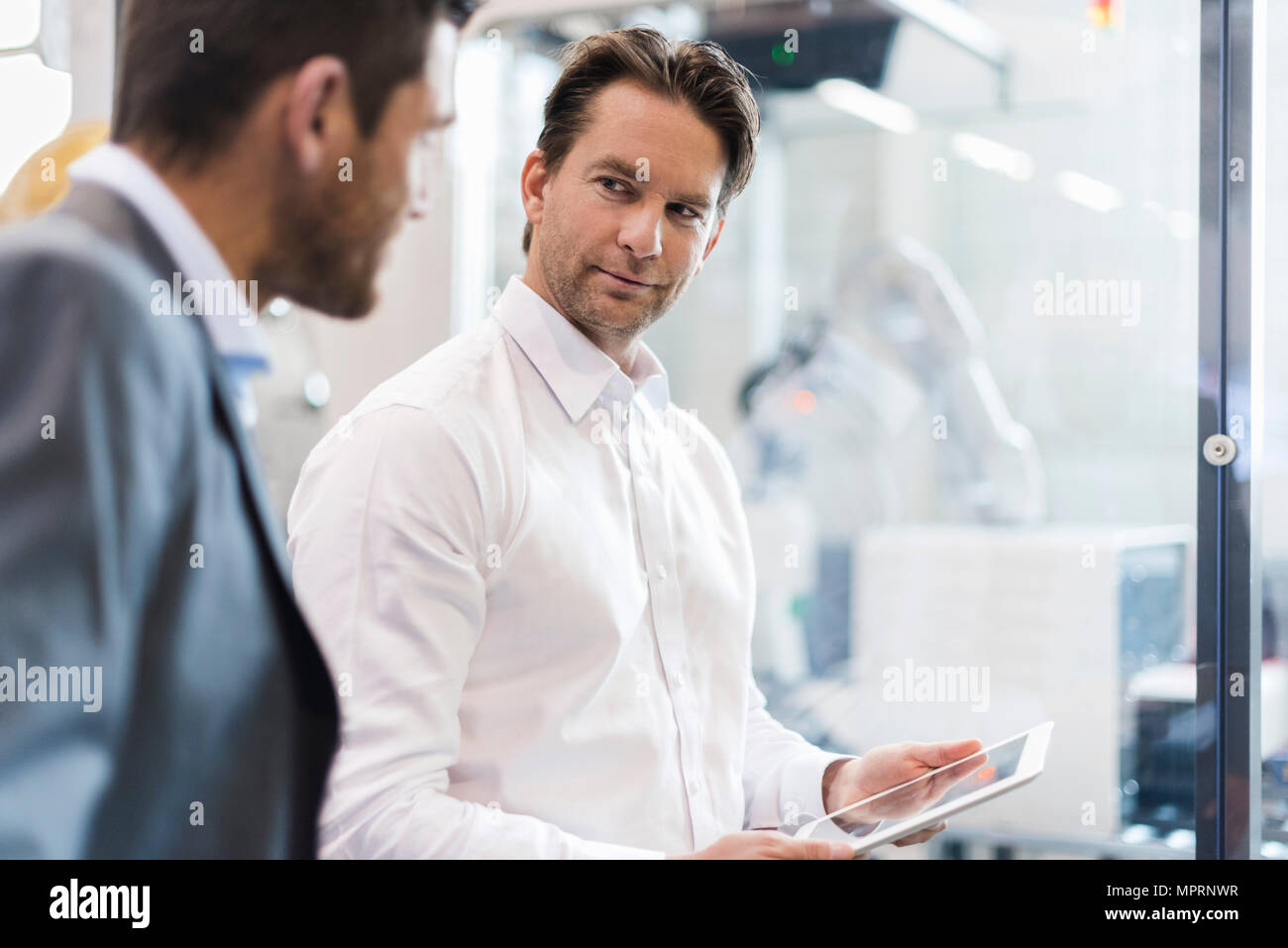 Zwei Geschäftsleute mit Tablet sprechen in der modernen Fabrik Stockfoto