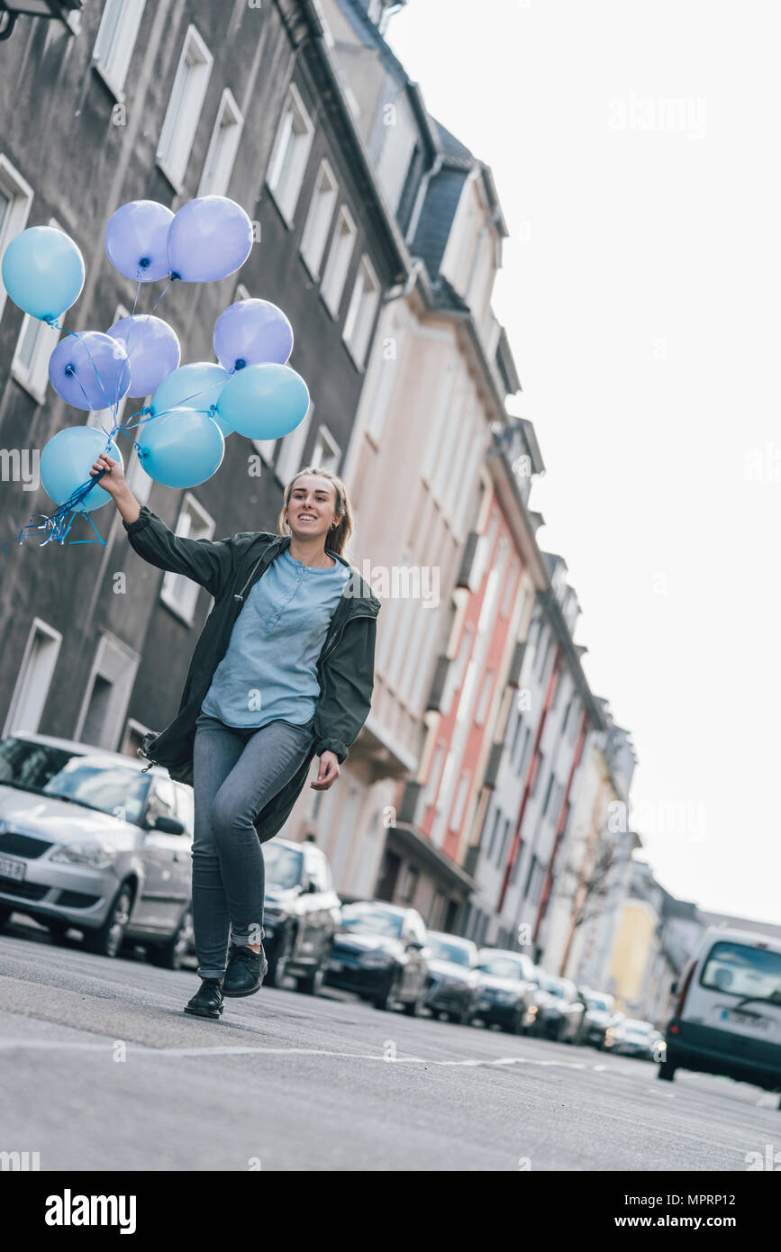 Gerne Frau mit blauen Ballons gehen auf die Straße Stockfoto
