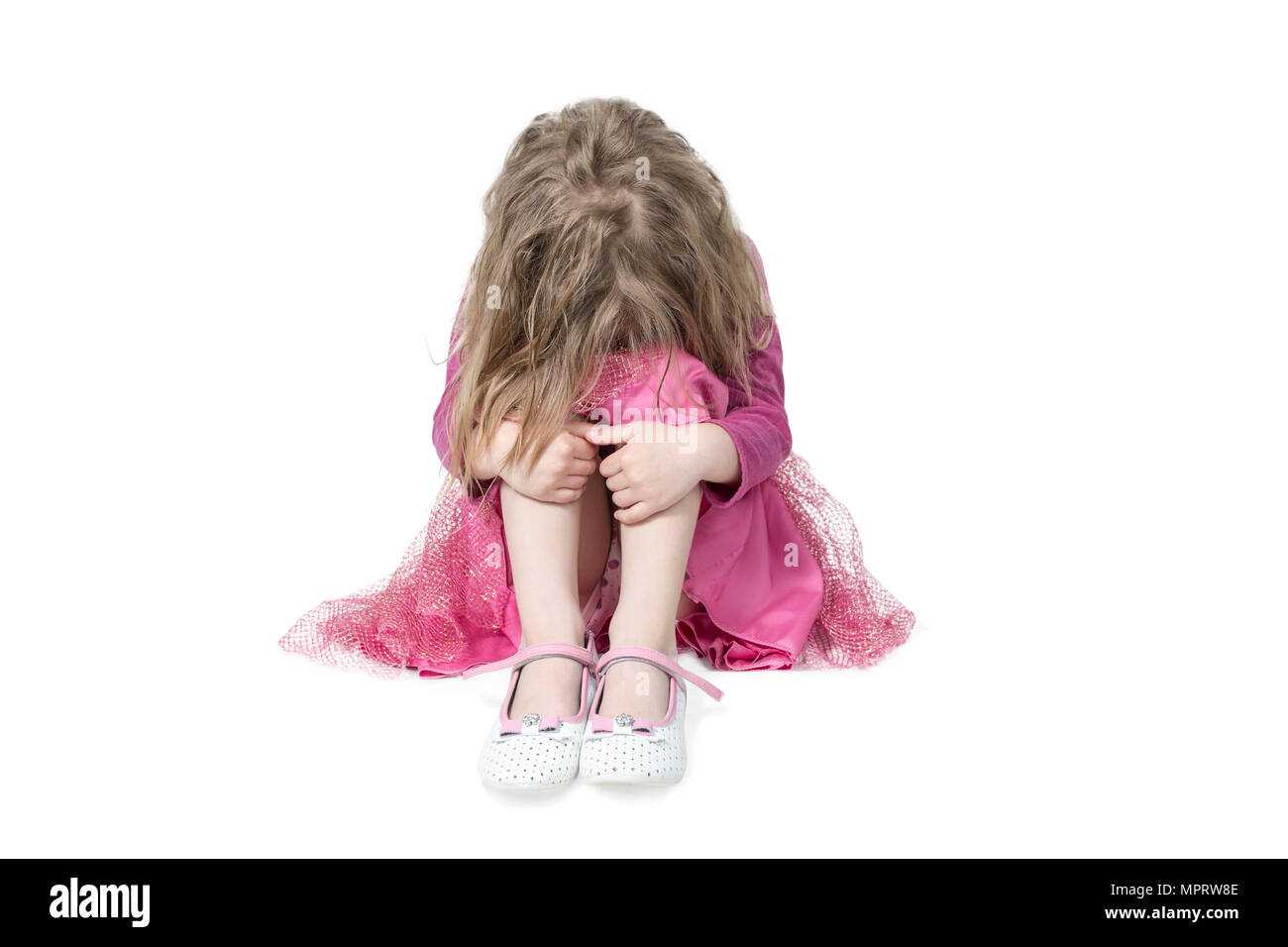 Porträt von einem weinenden Mädchen sitzen auf dem Boden, mit einem Zerzausten hairdress ihre Knie umfassen, auf weißem Hintergrund Stockfoto
