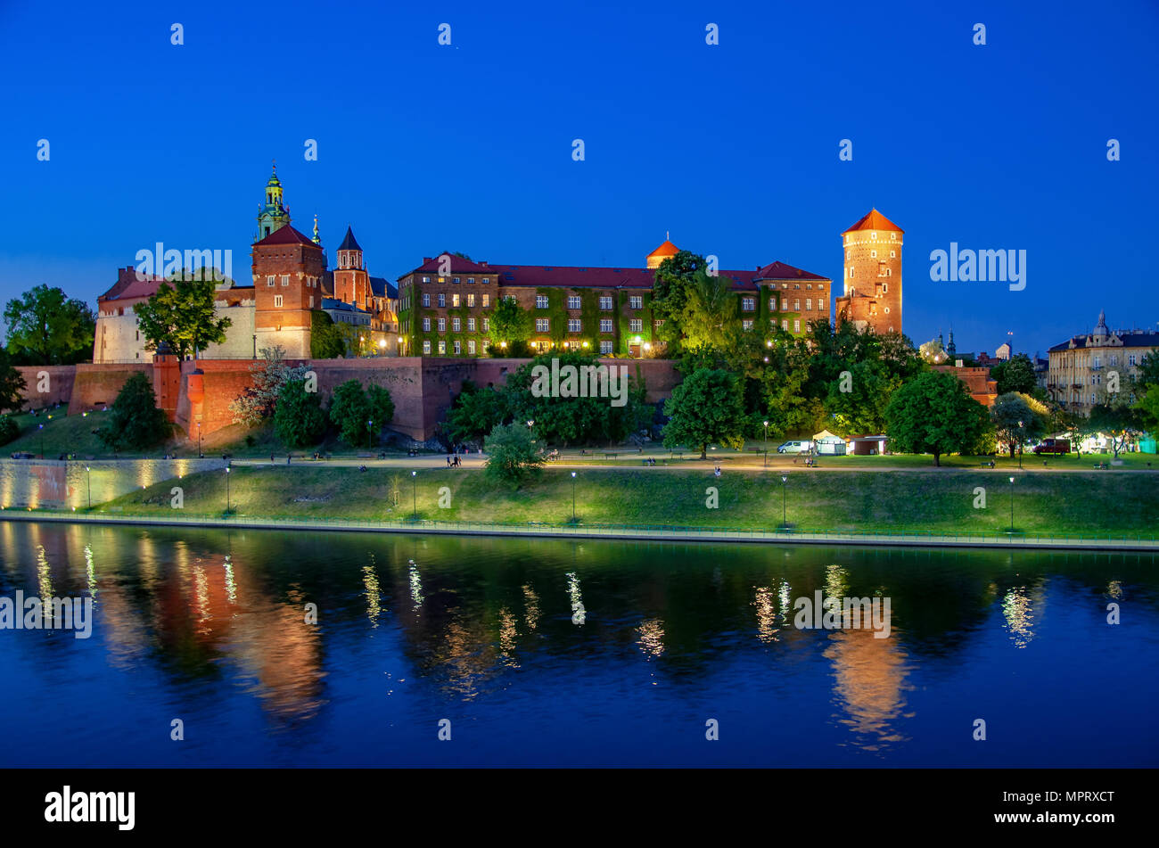 Polen, Krakau. Beleuchtete königliche Schloss Wawel und Dom bei Nacht und ihre Reflexion in der Weichsel. Riverside mit Park, Bäume, Promenade und l Stockfoto
