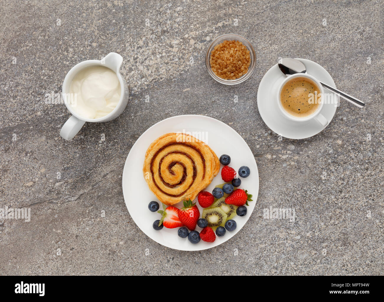 Kontinentales Frühstück mit einem Cinnamon Swirl, Obst und Kaffee, Schuß auf einen Stein Küche Arbeitsplatte, von oben. Stockfoto