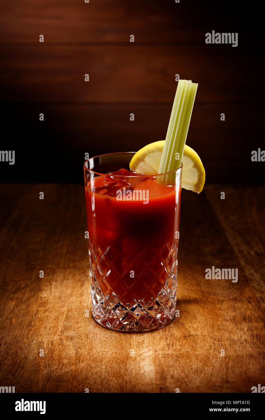Spotlight auf einen Kristall Gläser voll der Bloody Mary Cocktail, mit Sellerie garnieren, Schuß auf einem antiken Holztisch. Stockfoto