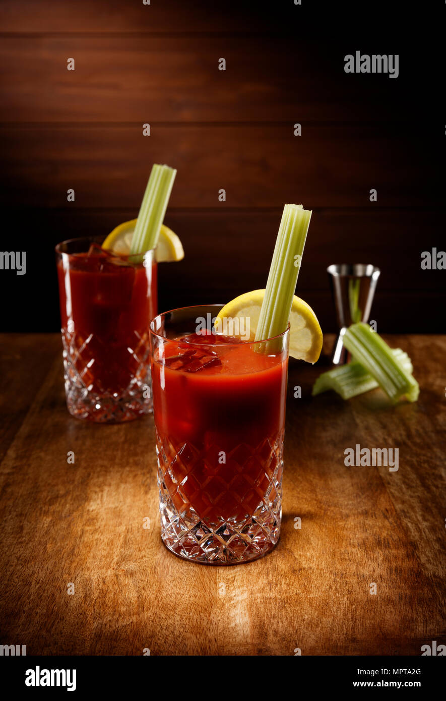 Spotlight auf zwei Kristallgläser voll der Bloody Mary Cocktail, mit Sellerie garnieren, Schuß auf einem antiken Holztisch. Stockfoto