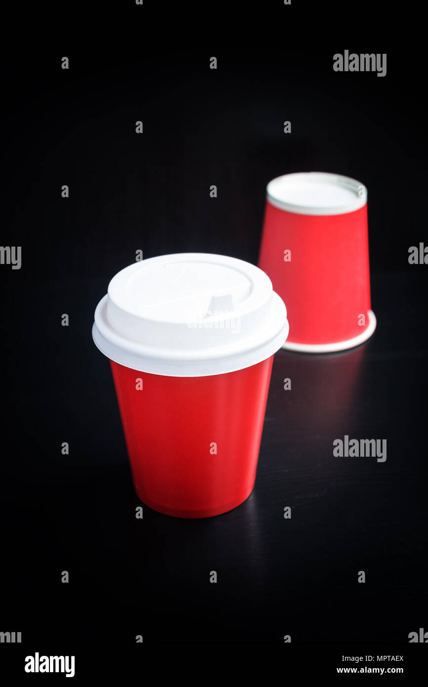 Red Kaffeetassen auf schwarzem Hintergrund. Coffee to go Stockfoto