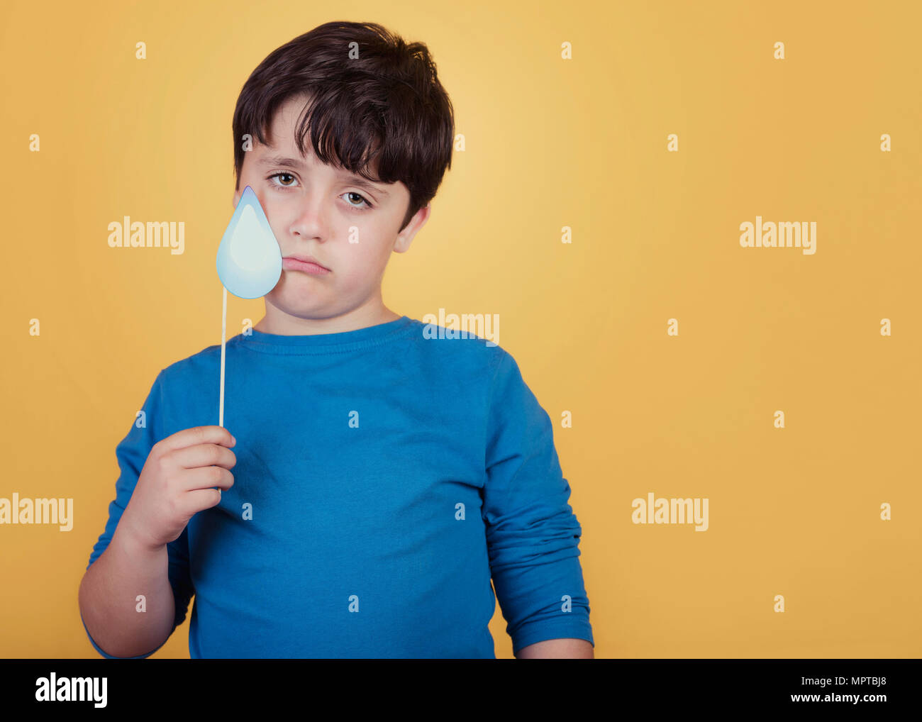 Traurige Junge mit einem Karton auf gelben Hintergrund reißen Stockfoto
