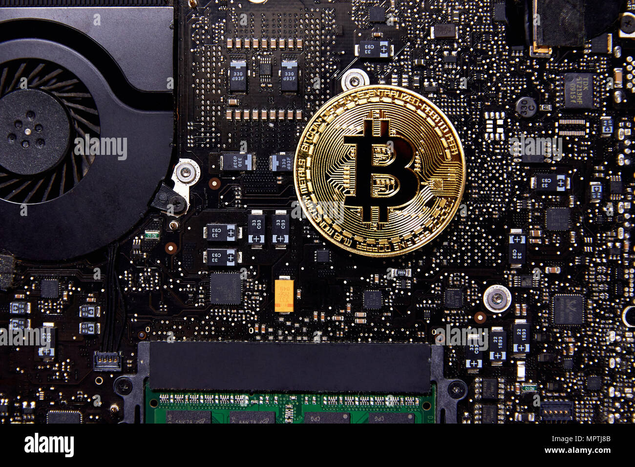 Eine Bitcoin physischen Münze sitzen auf einem Computer Motherboard mit Lüfter und RAM. Es ist das erste dezentrale Währung Stockfoto
