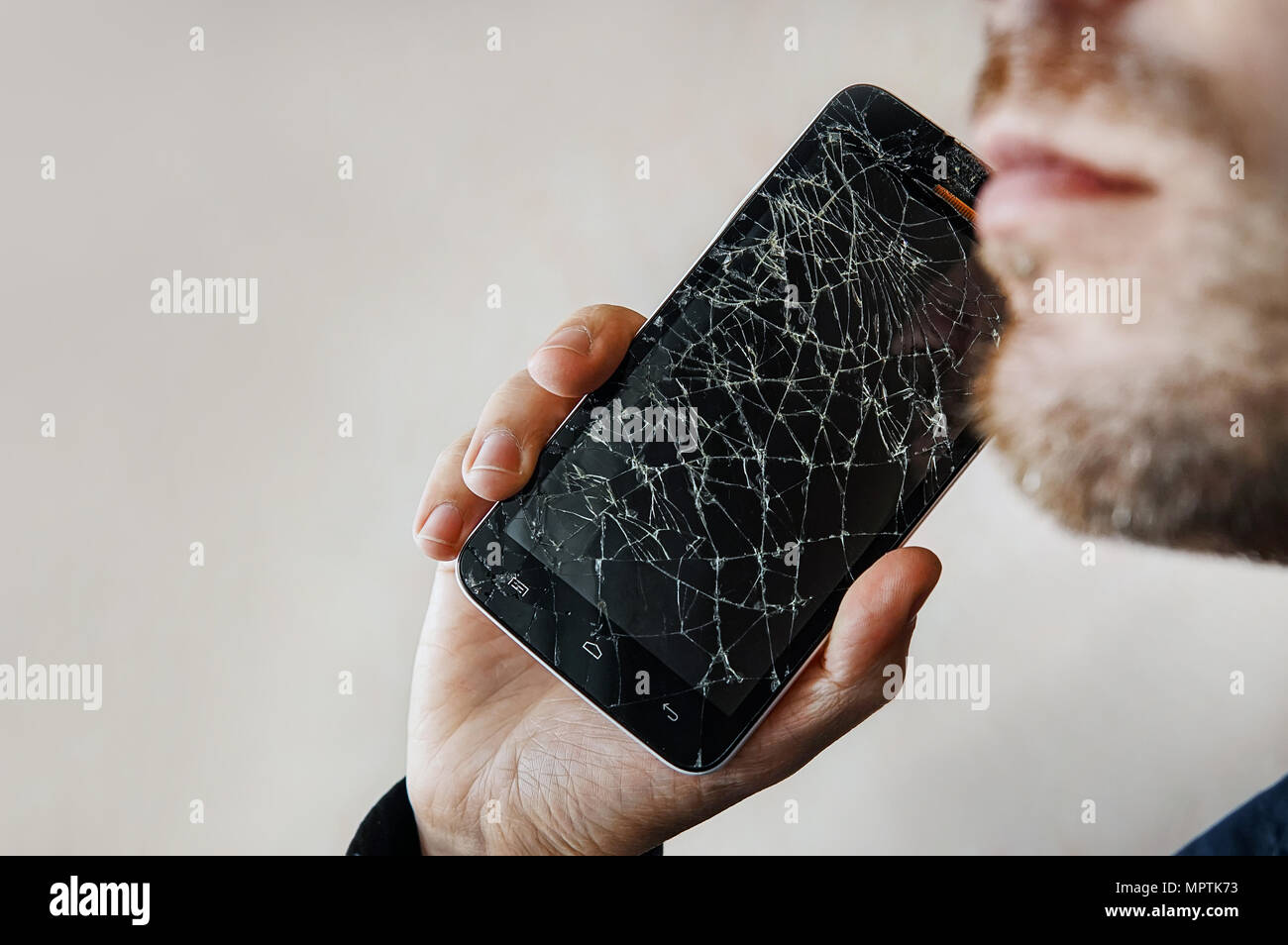 Der Kerl ist ein Gespräch mit einem defekten Bildschirm. BlackBerry-Smartphone mit zersprungenem Glas in der Hand eines Mannes. Kopieren Sie Raum. Copyspace. Stockfoto