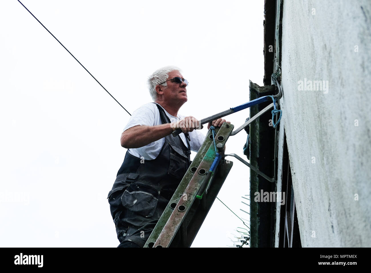 Ein Builder arbeiten auf einer Leiter die Regenrinne eines Hauses zu reparieren. Stockfoto