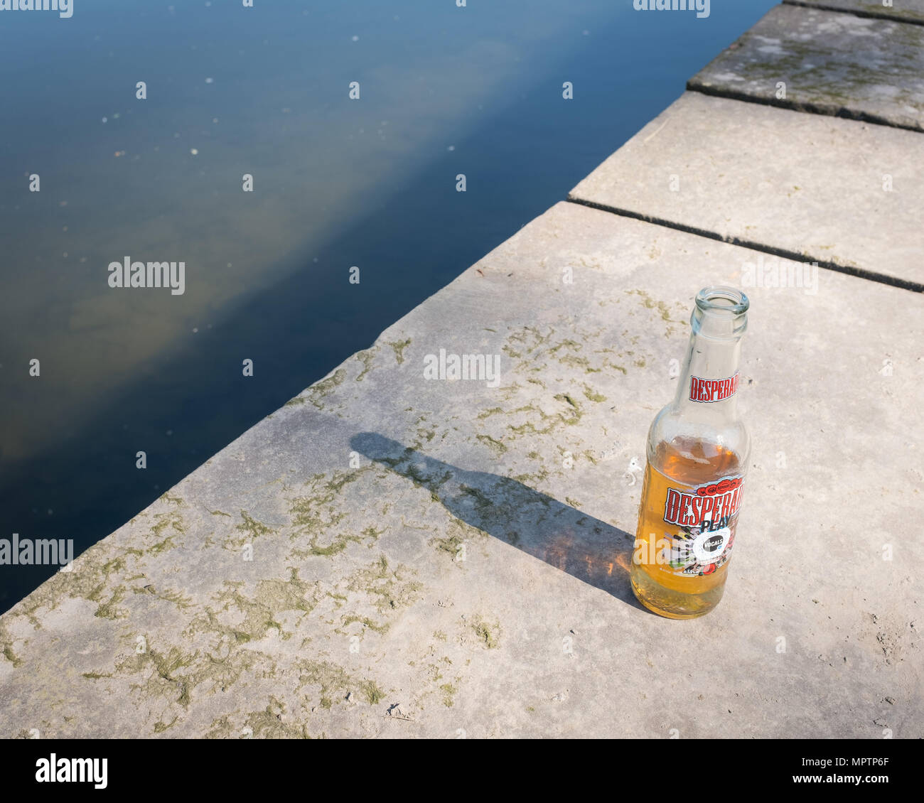 Halb leeren Flasche Desperados Bier links neben einem Fluss an einem sonnigen Morgen im Sommer verlassen. Stockfoto