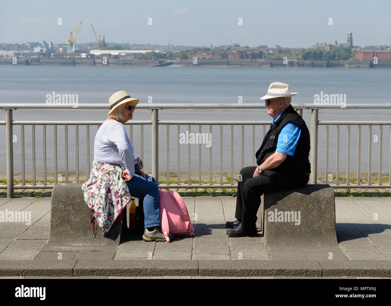 Ein älteres Ehepaar auf Poller an der Seite des Flusses Mersey an einem warmen sonnigen Tag in Liverpool, England, UK Stockfoto