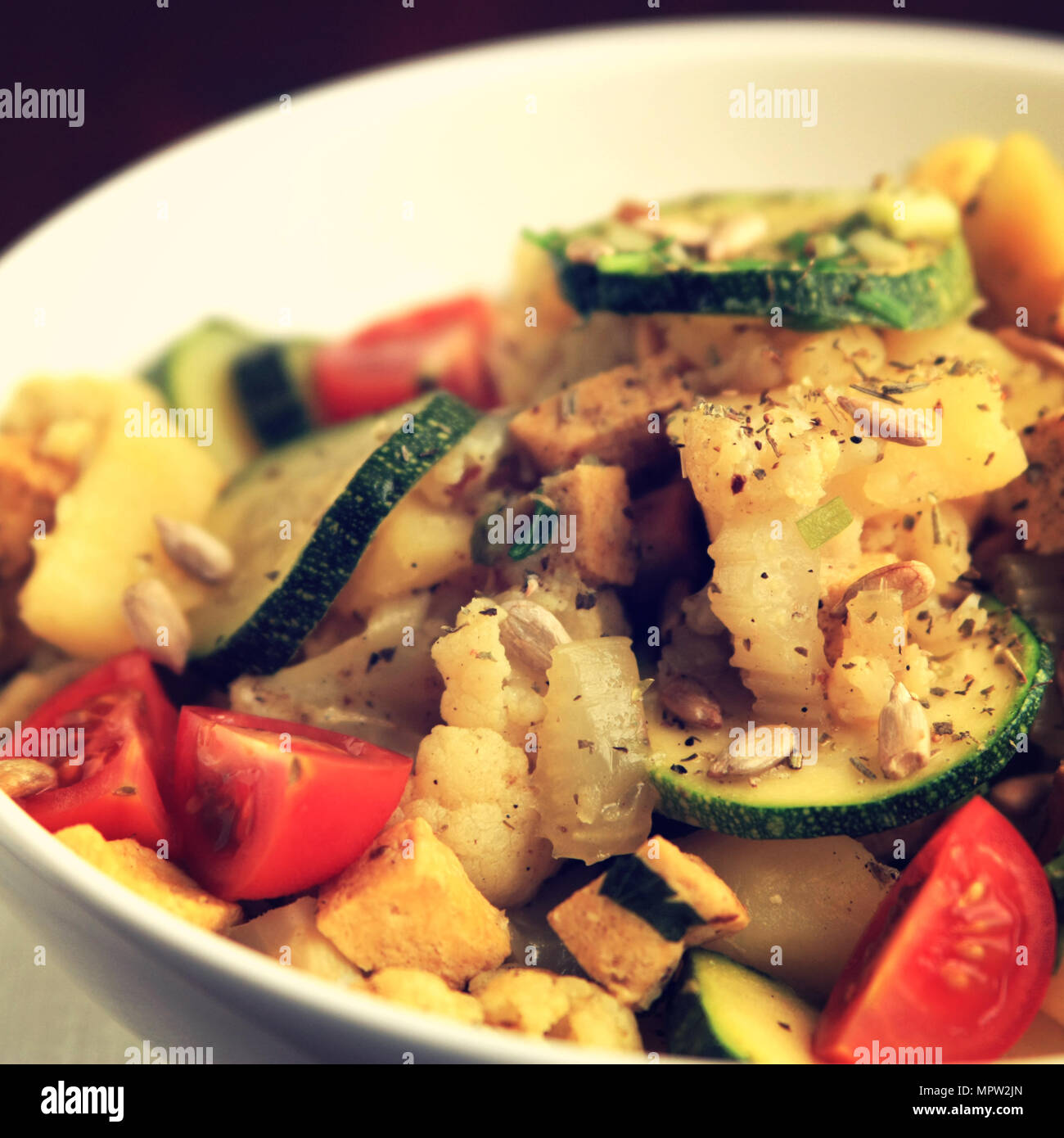 Gemüseeintopf mit Tofu, Blumenkohl und Zucchini garniert mit Sonnenblumenkernen. Europäische Küche. Gesund vegan Mittagessen in der Schüssel. Hauptgericht. Vegeta Stockfoto