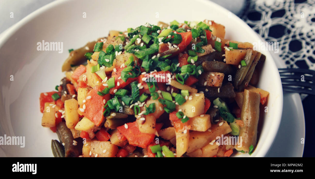Gemüseeintopf mit Kartoffel, Karotte und grüne Bohnen mit Sesam. Europäische Küche. Gesund vegan Mittagessen auf der Runde weiße Platte. Europäische Stockfoto